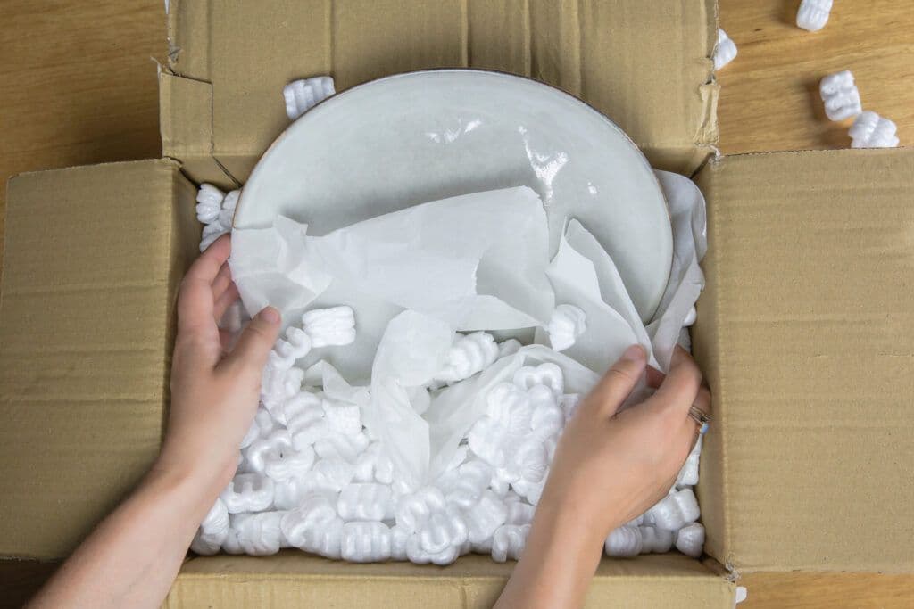 Persoon pakt verhuisdozen in met inpakpapier